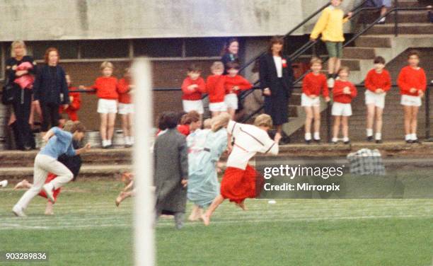 The Princess of Wales, Princess Diana runs in her sons William and Harry's School Sports Day. She is wearing the white top and long red skirt. The...