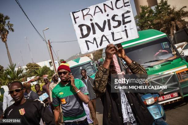 Group of demonstrators, one holding a placard that reads "France divides Mali", marching towards the French Embassy in Bamako to protest against the...