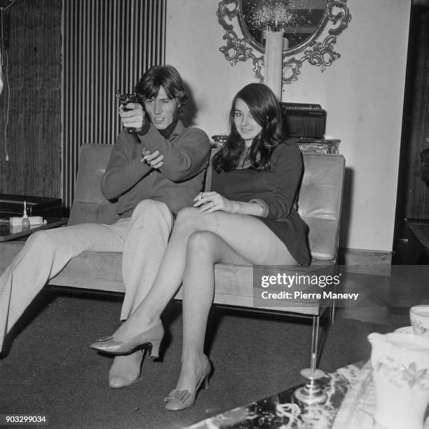 British singer and songwriter Barry Gibb pointing a gun, while sitting next to his girlfriend, former Miss Edinburgh Linda Gray, UK, 19th October...