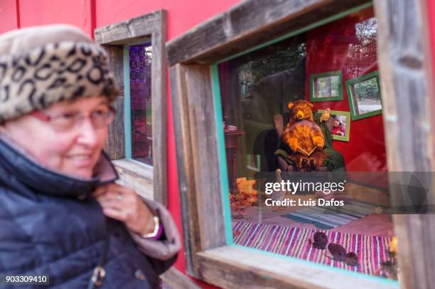 a smiling woman walks past a children´s life sized toy house with tedy bears. - s christmas festival stock-fotos und bilder