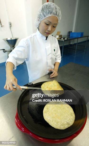 Worker demonstrates the way of cooking instant Indian pancakes at Tee Yih Jia food manufacturing in Singapore 11 June 2002. As Singapore searches for...