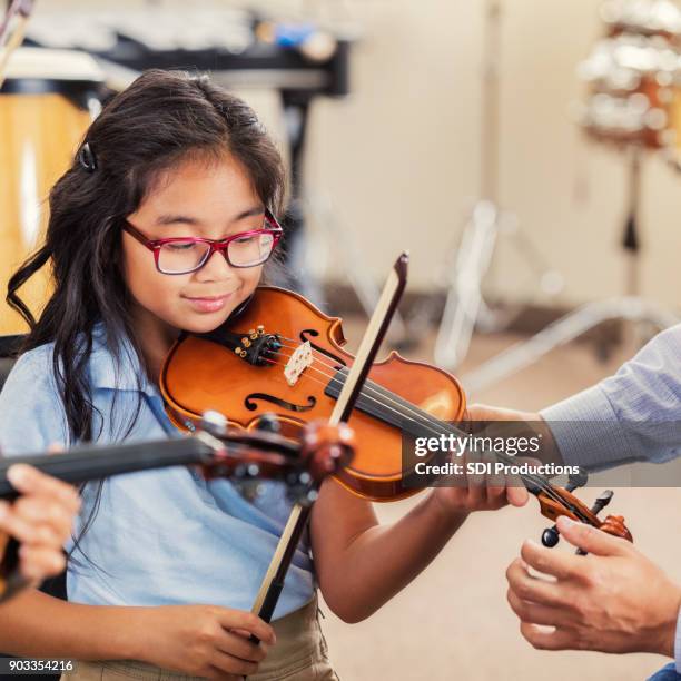 elementary age girl enjoys violin class at school - kid conductor stock pictures, royalty-free photos & images