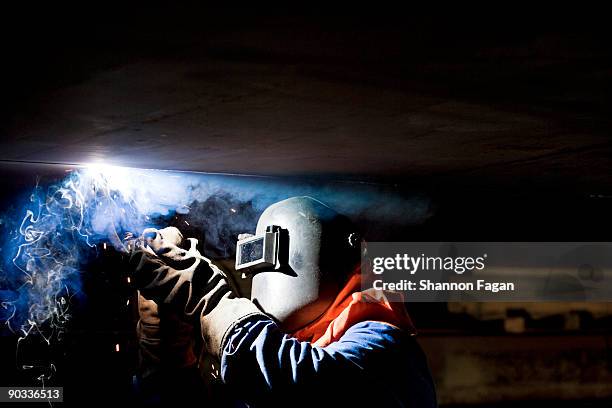 a man with hard mask welding an oil container - 溶接 ストックフォトと画像