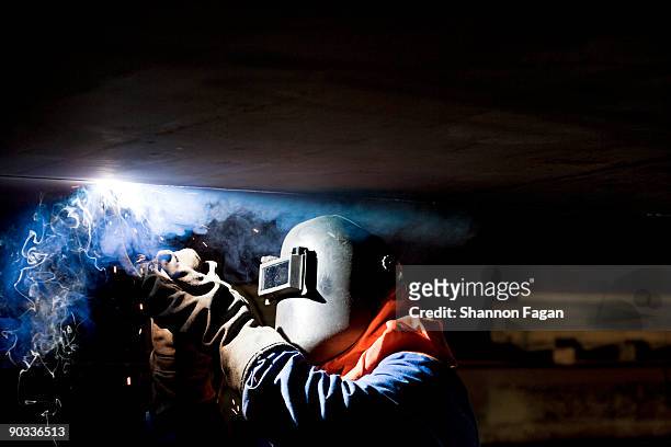 a man with hard mask welding an oil container - in flames i the mask stock pictures, royalty-free photos & images