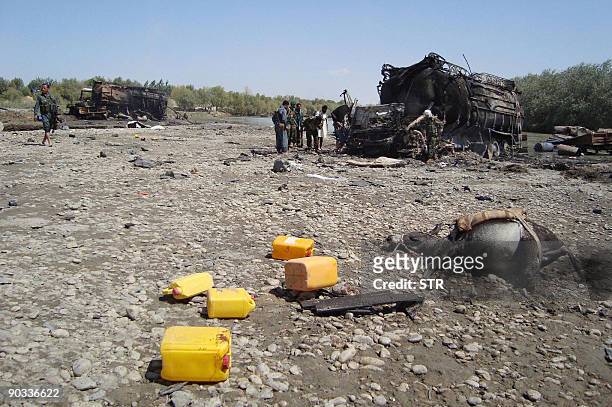 Members of the security forces walk at the site of a NATO airstrike which destroyed two fuel tankers hijacked by the Taliban in northern Kunduz on...