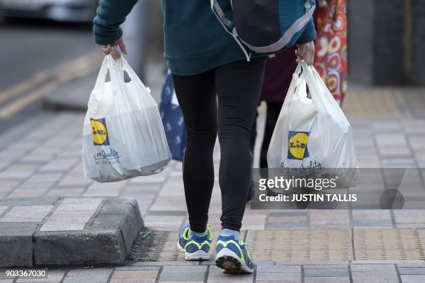 Person leaves with their goods in plastic carrier bags after shopping at a branch of Lidl in south Londo on January 10, 2018.