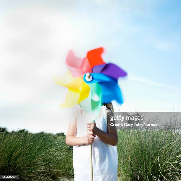 girl holding a pinwheel in sea grass & sand dunes - windrad spielzeug stock-fotos und bilder