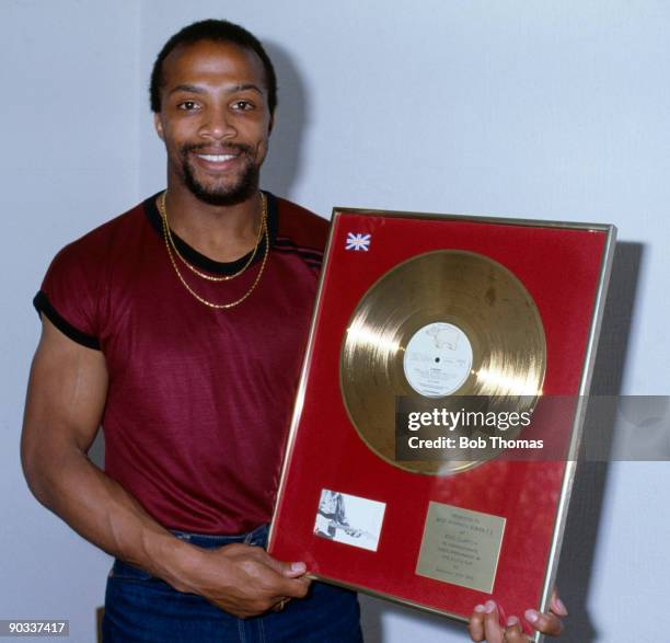 Cyrille Regis of West Bromwich Albion holding a framed gold record disc, given to him by musician Eric Clapton, circa 1982.