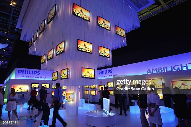 Visitors stand under a display of flat screen televisions at the Philips stand on opening day at the IFA technology trade fair on September 4, 2009...