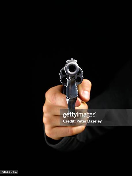 gun pointing at camera on black background. - hand holding gun stockfoto's en -beelden