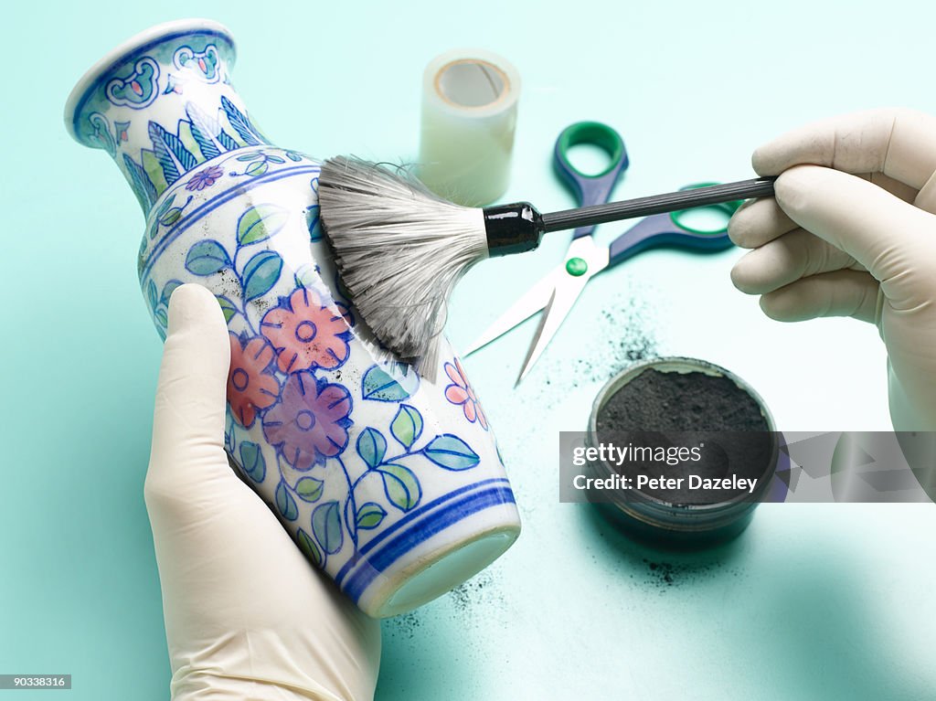 Forensic scientist dusting vase for fingerprints.