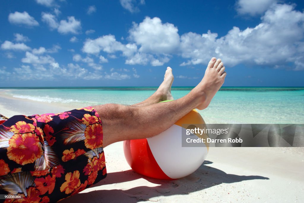 Man relaxing with feet resting on a beach ball