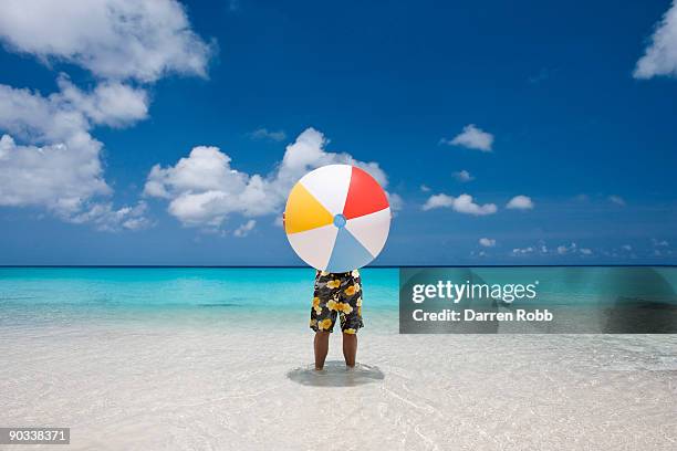 man holding a giant beach ball on tropical beach - bermuda beach imagens e fotografias de stock