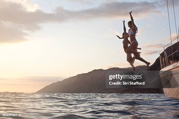 two girls jumping off of boat - sailboat silhouette stock pictures, royalty-free photos & images