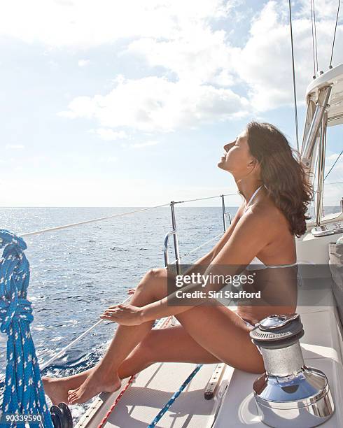 young woman soaking up sun on sailboat - siri stafford fotografías e imágenes de stock