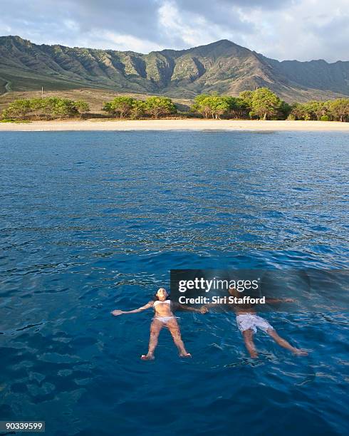 young man and woman floating and holding hands - siri stafford stock pictures, royalty-free photos & images