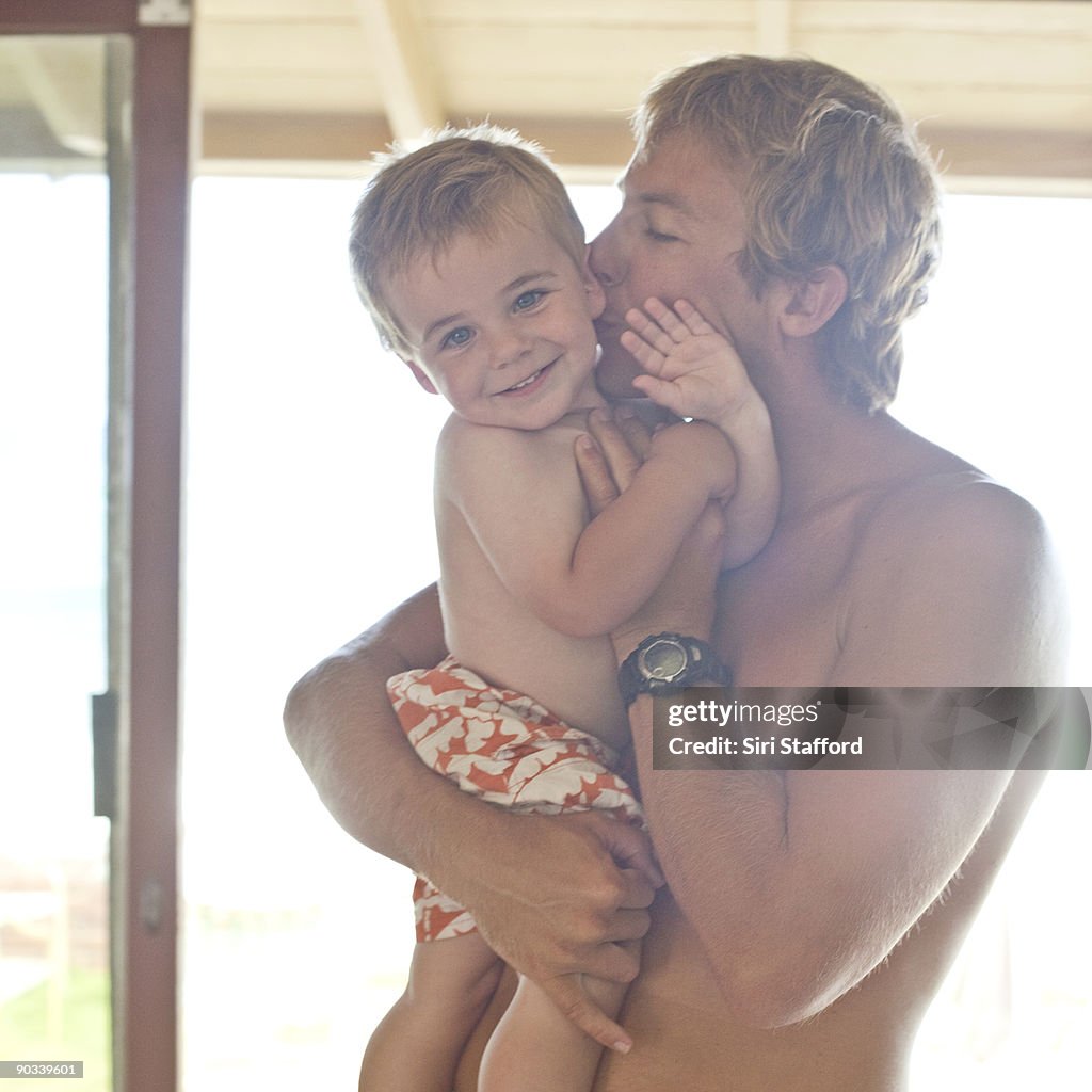 Young boy smiling while father gives hug and kiss