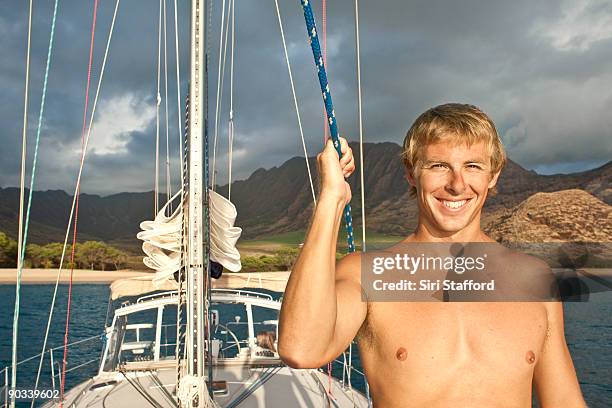 young man on sailboat at sunset, smiling - siri stafford fotografías e imágenes de stock