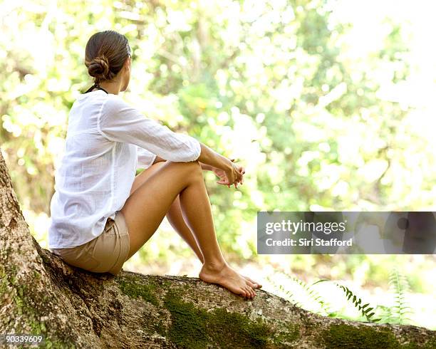 young woman relaxing on tree root in jungle - siri stafford fotografías e imágenes de stock