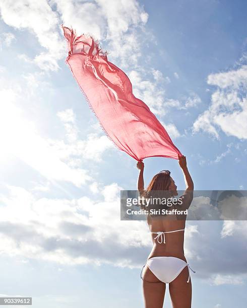 young woman holding sarong aloft - siri stafford stock pictures, royalty-free photos & images