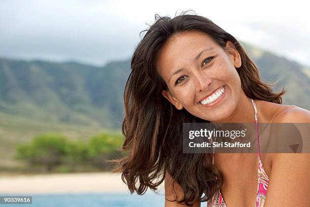 young woman smiling with tropical beach behind her - siri stafford fotografías e imágenes de stock