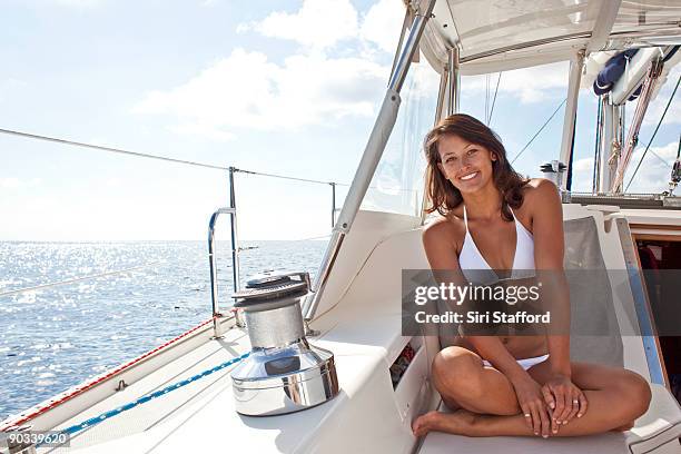 young woman sitting on sailboat in bikini, smiling - siri stafford fotografías e imágenes de stock