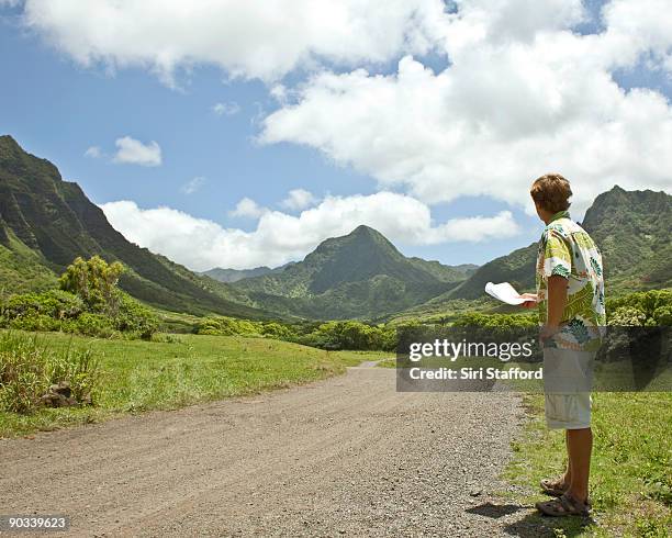 man on dirt road with directions in hand - siri stafford fotografías e imágenes de stock