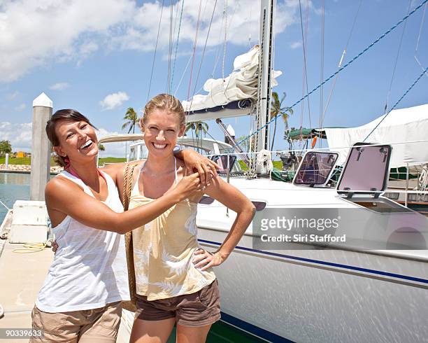two young women standing next to sailboat - siri stafford fotografías e imágenes de stock