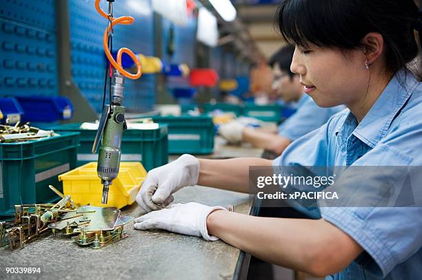 a woman bolting parts of hardware - production line imagens e fotografias de stock