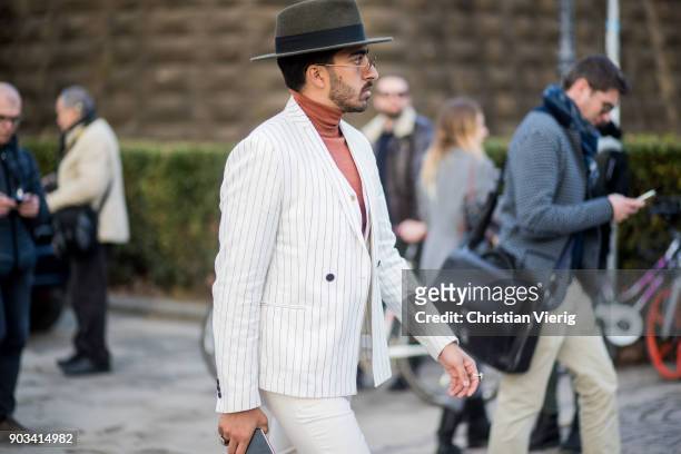 Guest wearing white suit, hat, turtleneck is seen during the 93. Pitti Immagine Uomo at Fortezza Da Basso on January 10, 2018 in Florence, Italy.