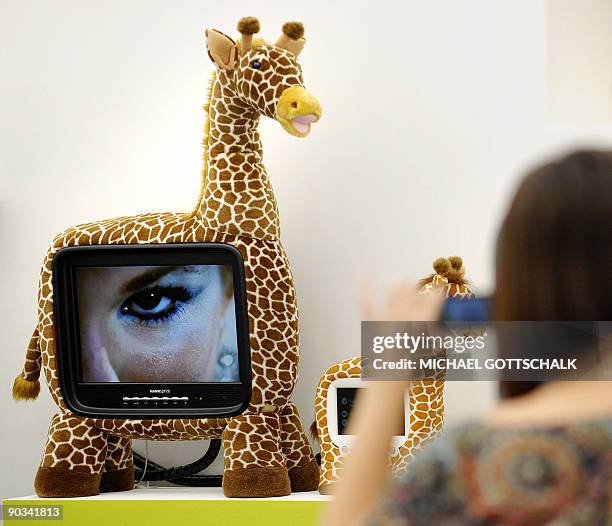 Fairgoer takes a picture of a toy giraffe with a built in TV screen on display at the IFA International Consumer Electronics Trade Fair, at Berlin's...