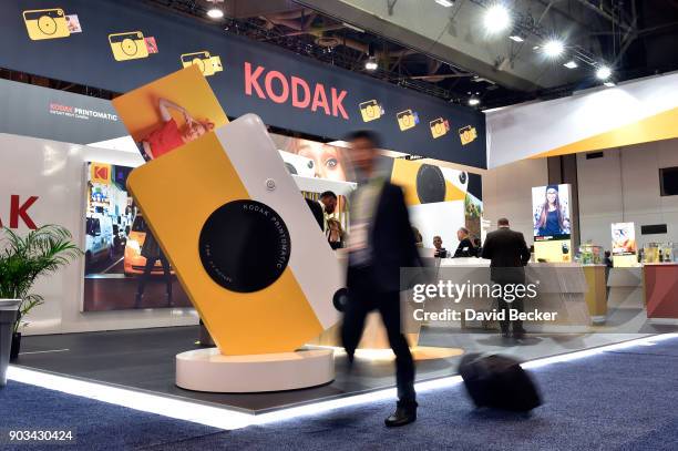 Using a slow shutter speed an attendee is blured as he walks by the Kodak booth during CES 2018 at the Las Vegas Convention Center on January 10,...