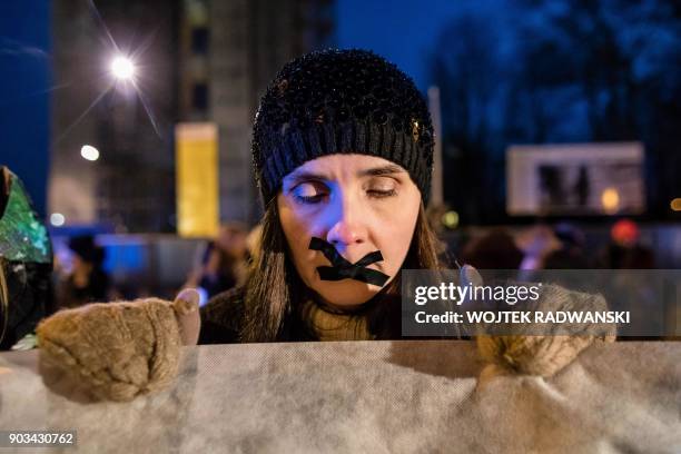 Woman, with tape on her mouth, holds a banner during an anti-government and pro-abortion demonstration on January 10, 2018 outside the Parliament in...