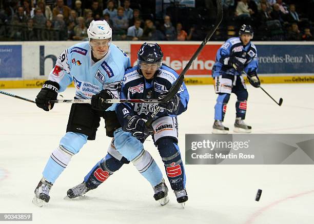 Elia Ostwald of Hamburg and Andy Canzanello of Straubing fight for the puck during the DEL match between Hamburg Freezers and Straubing Tigers at the...