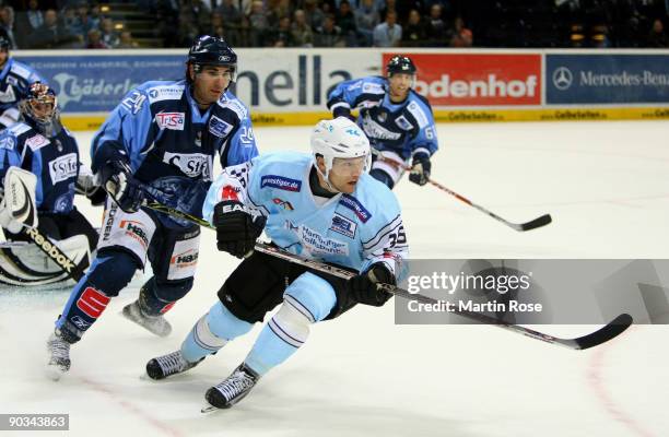 Alexander Dotzler of Hamburg and Calvin Elfring of Straubing fight for the puck during the DEL match between Hamburg Freezers and Straubing Tigers at...