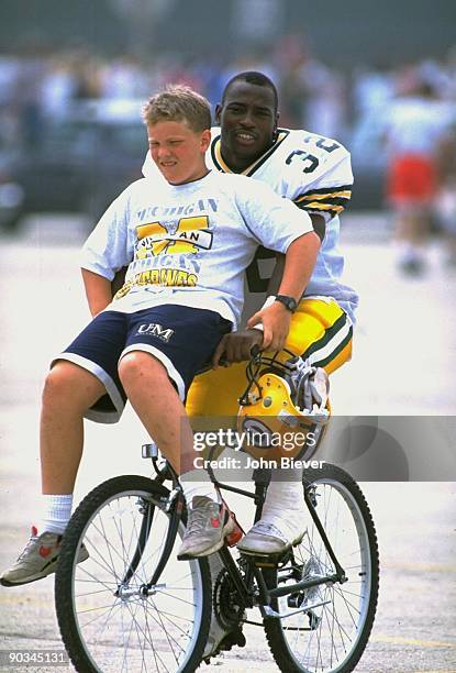 Green Bay Packers John Stephens riding bicycle with youth fan on handlebar during training camp at St. Norbert College. De Pere, WI 7/19/1993 CREDIT:...