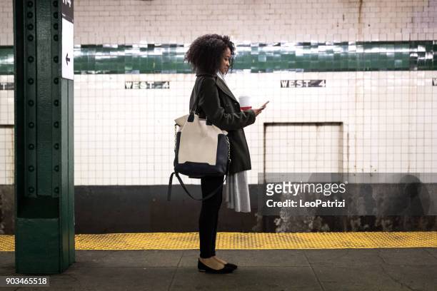 giovane donna in attesa del treno della metropolitana a new york - pendolare foto e immagini stock