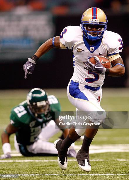 Damaris Johnson of the Tulsa Golden Hurricanes runs past Charles Harris of the Tulane Green Wave at the Louisiana Superdome on September 4, 2009 in...