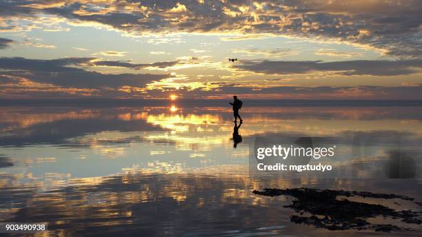 travelist having fun with drone on salt lake at sunset - drone pilot stock pictures, royalty-free photos & images