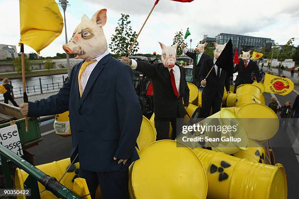 Mannequins dressed as pigs and meant to represent politicians standing among nuclear waste barrels stand on a tractor among anti-nuclear protesters...