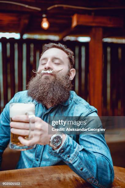 knappe bebaarde hipster persoon drinken bier in de pub en genieten van - man sipping beer smiling stockfoto's en -beelden