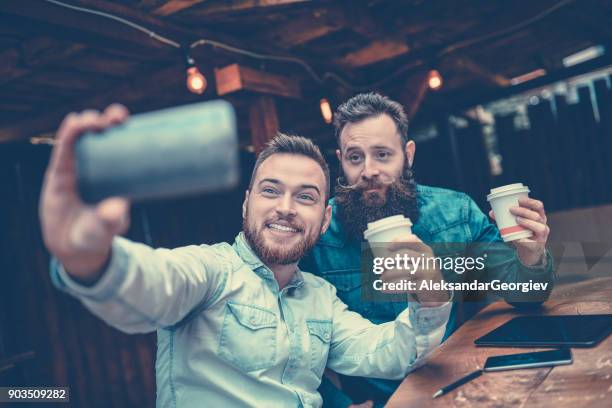 zwei bärtigen freunde, trinken kaffee und nehmen selfie in restaurant - couple beard coffee stock-fotos und bilder