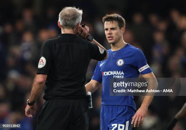 Referee Martin Atkinson listens to his Assistant on his ear-piece during the Carabao Cup Semi-Final first leg match between Chelsea and Arsenal at...
