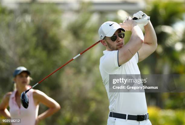 Singer Nick Jonas plays a shot as model and actress Kelly Rohrbach looks on during the pro-am tournament prior to the Sony Open In Hawaii at Waialae...