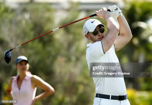 Singer Nick Jonas plays a shot as model and actress Kelly Rohrbach looks on during the pro-am tournament prior to the Sony Open In Hawaii at Waialae...