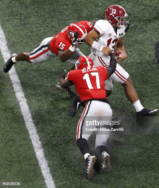 Quarterback Tua Tagovailoa of the Alabama Crimson Tide is pursued by linebackers Davin Bellamy and D'Andre Walker during the College Football Playoff...