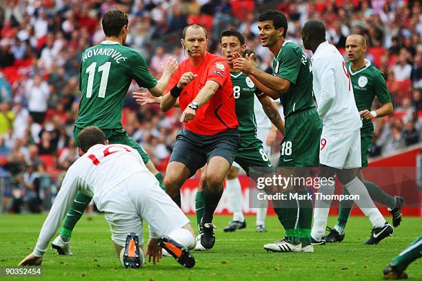 Referee Jonas Eriksson is surrounded as he awards a penalty against Bostjan Cesar of Slovenia for a foul on Wayne Rooney of England during the...