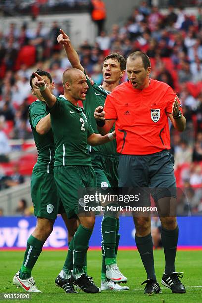 Slovenia players surround Referee Jonas Eriksson as he awards a penalty against Bostjan Cesar of Slovenia for a foul on Wayne Rooney of England...