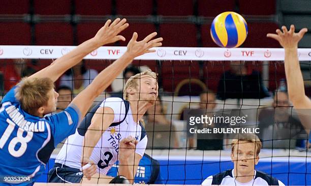Mikko Esko of Finland spikes the ball over the net as Estonia`s Jaanus Nommsalu and Ardo Kreek jump to block it during their European Volleyball...
