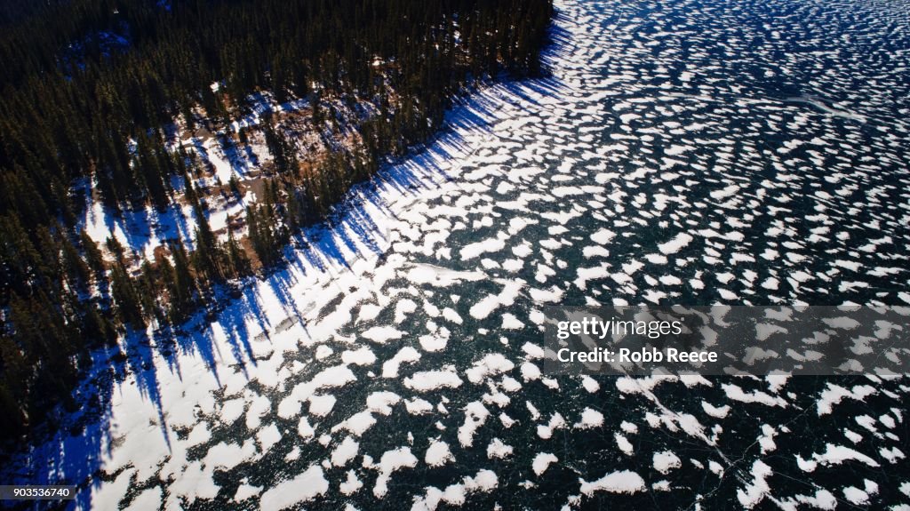 White Landscapes - Frozen lake with ice patterns and trees in winter.